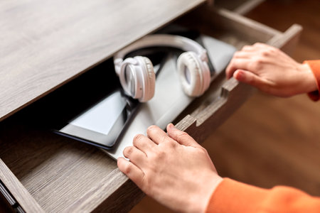 hands and different gadgets in desk drawer at homeの写真素材