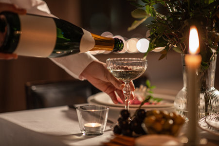 champagne pouring from bottle to glass on tableの写真素材