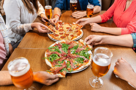 friends eating pizza with beer at restaurantの写真素材