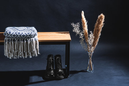 blanket on bench, boots and plants in dark roomの写真素材