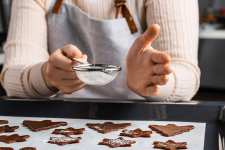 hands sifting sugar through sieve to gingerbreadの写真素材