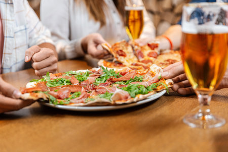 friends eating pizza with beer at restaurantの写真素材