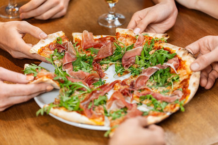close up of friends eating pizza at restaurantの写真素材