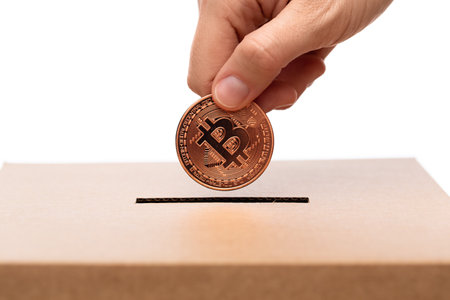 hand putting bitcoin into charity donation boxの写真素材