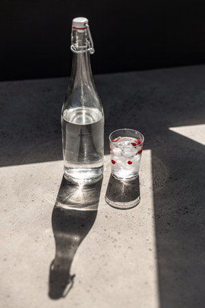 bottle of water and glass with ice and cranberriesの写真素材