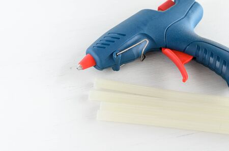 Blue glue gun and hot melt rods on white background.の写真素材