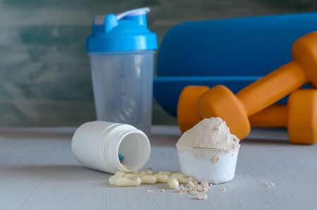 Protein powder in scoop, dumbbell, yoga mat and shaker. Fitness and sport conceptの写真素材