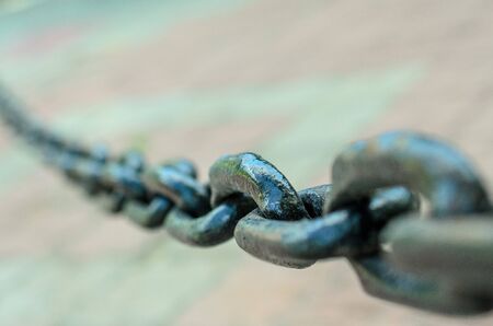 Big links of dark metal chain in sity street, closeup.の写真素材