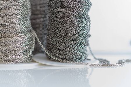 Coils with metal bijouterie chains on a white background. Jewelry making.