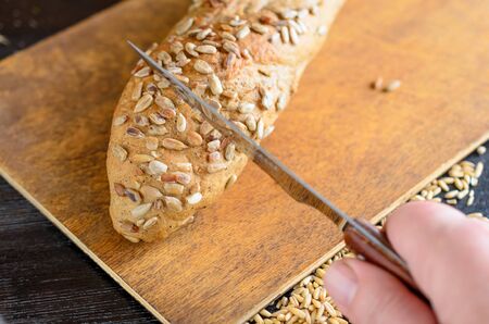 Fresh whole grain bread with kitchen knife on the kitchen. Healthy eating.