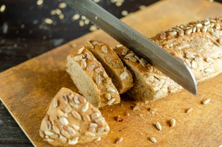 Fresh whole grain bread with kitchen knife on the kitchen. Healthy eating.