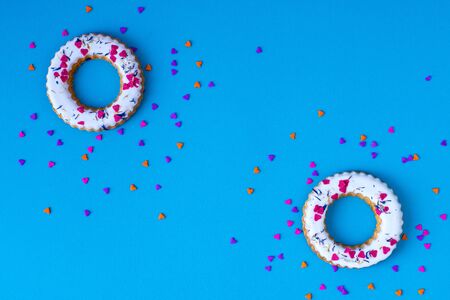 Creative layout made of glazed ring shape rolls, bagels with colorful hearts. Flat lay. Nature concept. Conceptual greeting card. Colorful spring background, space for text. Trendy Decorative Design.の写真素材