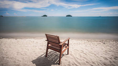 Wood chair on a  sand beach in front of the sea.  Long exposureの写真素材
