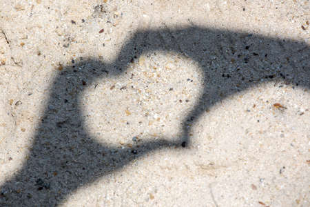 two hands forming a heart shadow on the Sandの写真素材