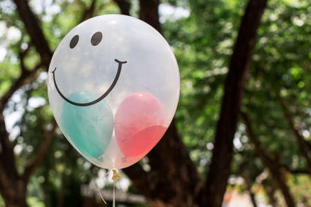 Transparent  balloon with smile face on green bokeh の写真素材