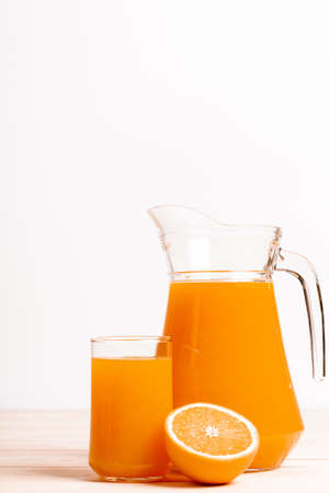 glass and jar of fresh orange juice with fresh orange on wood tableの写真素材