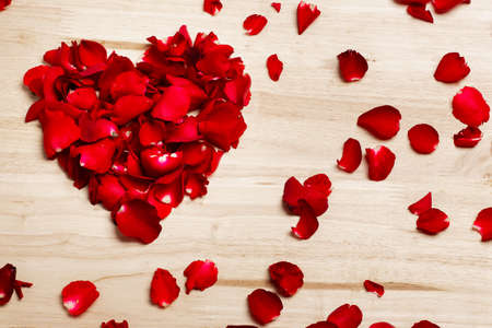 red rose petals heart shape  on wooden background