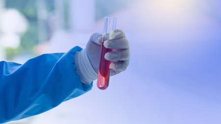 Hand hold up the glass tube filled with red liquid. Copy space to use.の写真素材