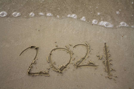 2021 number year written on sand with waveの写真素材