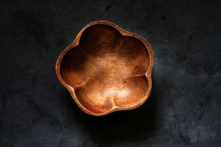 Empty wooden bowl on black surfaceの写真素材