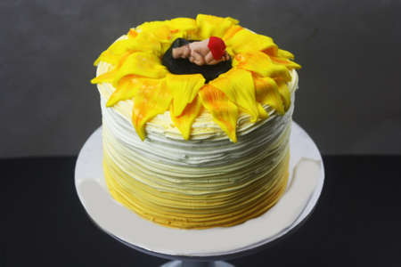 Sunflower inspired cake with baby sleeping figurines at cake topの写真素材