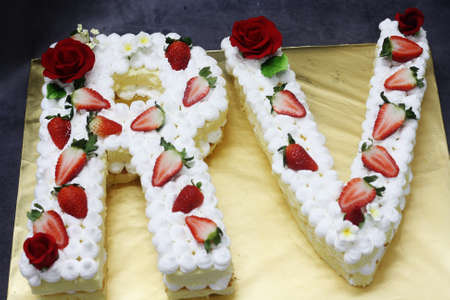 Monogram cake shape with R & V letters, top with flower and strawberryの写真素材