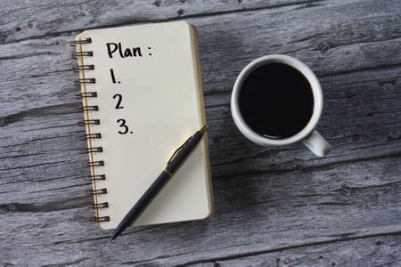 Selective focus Plan written on note pad with cup of coffe on the side. Top view