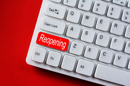 Reopening wording concept after the coronavirus pandemic. Keyboard with red color and white text. White keyboard on a red background.の写真素材