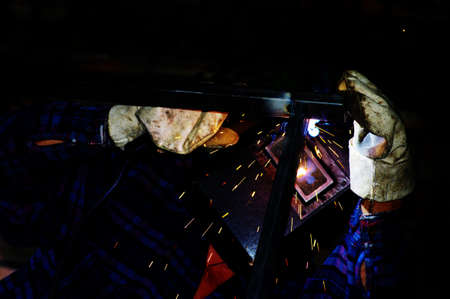 welder on the top of building welding metal.
