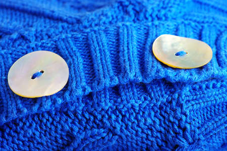 closeup of a wavy blue knitted fabric with buttons of boneの写真素材