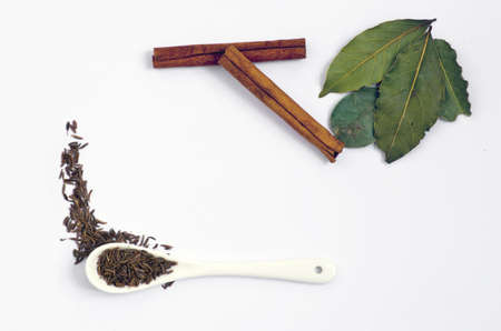 Spices. Spices in ceramic spoon over white background. Zira and cinnamon, bay