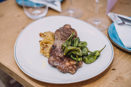 Tasty grilled steak with herbs on a white plate in a restaurant