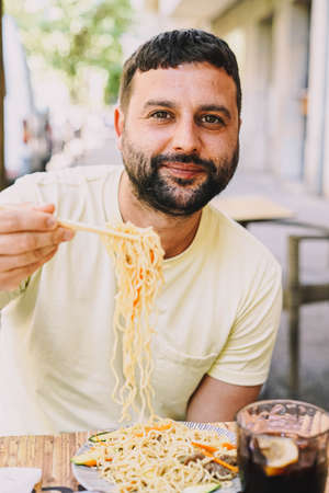Latino boy in yellow t-shirt eating japanese foodの写真素材