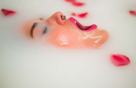 Woman relaxing in a bathtub with milk and rosesの写真素材