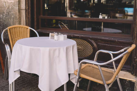 Set of table and chairs with a white tablecloth on the terrace of a barの写真素材