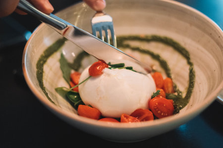 A caprese salad with burrata mozarella, cherry tomatoes and pesto sauceの写真素材