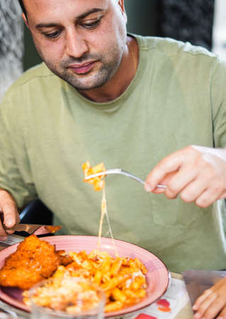 Man enjoying a plate of pasta with meat