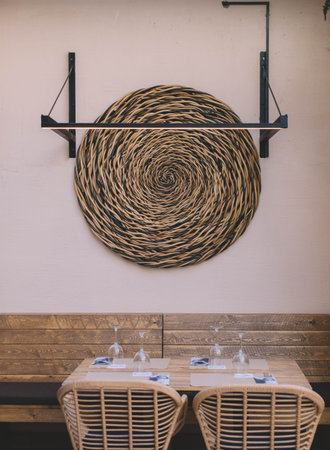 Interior design of a restaurant with wooden tables, chairs and a wicker chair