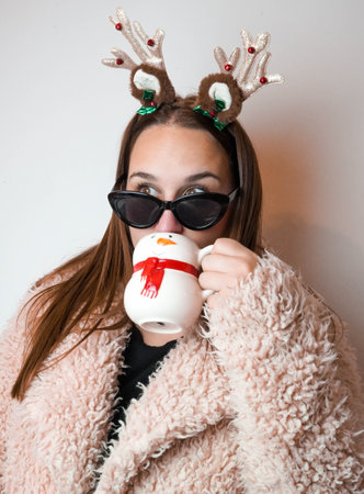 Girl enjoying christmas with a latte and reindeer headbandの写真素材