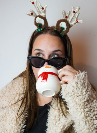 Girl enjoying christmas with a latte and reindeer headbandの写真素材