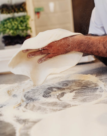 Hands of chef kneading dough in the kitchen at the bakery