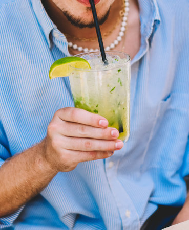 A young person enjoying a rum, lime and mint mojito