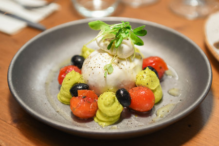 Caprese salad with mozzarella, tomatoes and olives on a plate