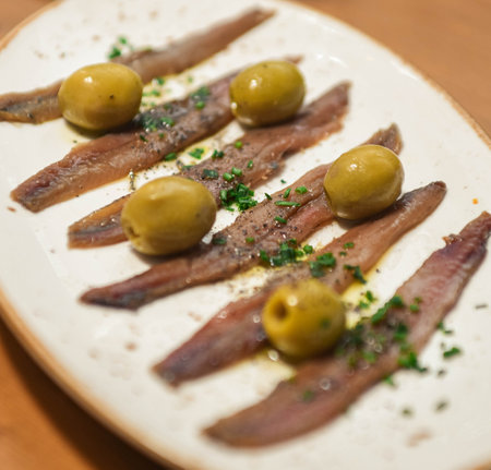 Marinated anchovies fillets with green olives on a plateの写真素材