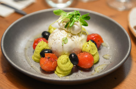 Caprese salad with mozzarella, tomatoes and olives on a plateの写真素材