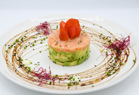 Salmon tartare with avocado and strawberry on white background in restaurantの写真素材