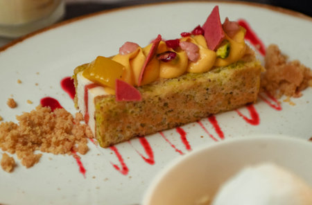 Fruit cake with orange, mango and strawberry sauce on white plate