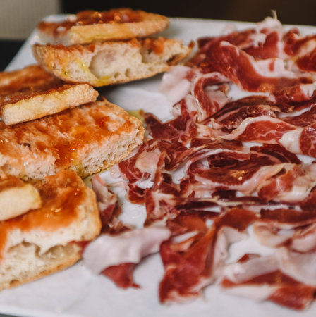 Sliced prosciutto and bread on a white plateの写真素材