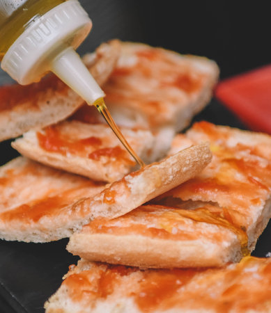Pouring olive oil on slices of toasted bread. Selective focus.