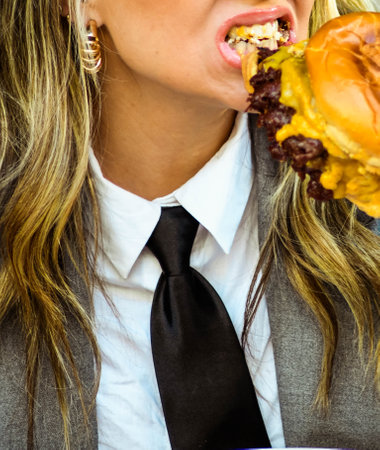 A young businesswoman eating a burger at an outdoor cafeの写真素材